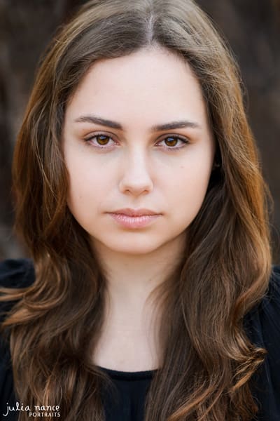 Moody actor headshot potrait of brunette woman with long curly hair.