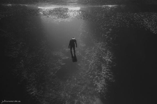 underwater photography of woman swimming in a cave