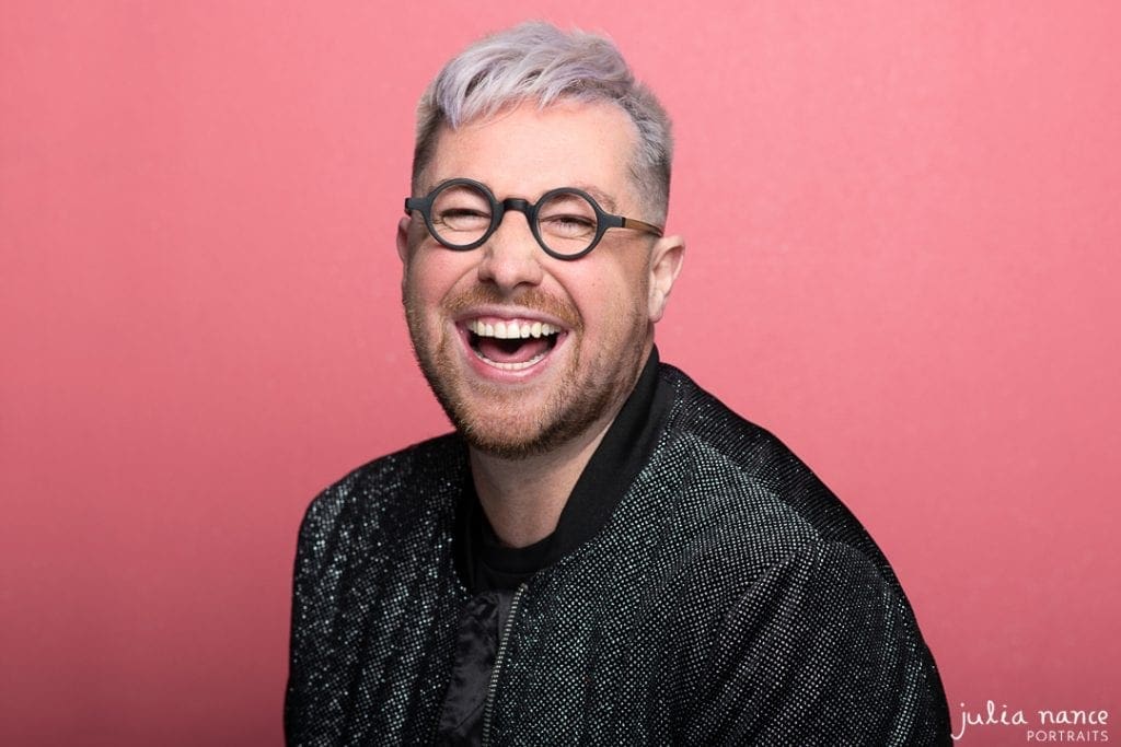 Melbourne actor laughs to camera on pink background in relaxed actor headshot.