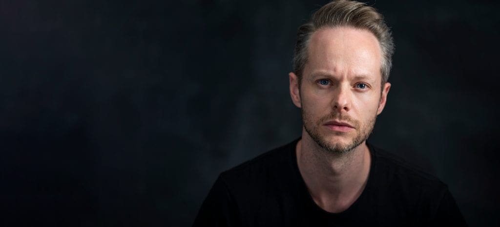 Serious actor headshot of melbourne man taken on dark background in studio.