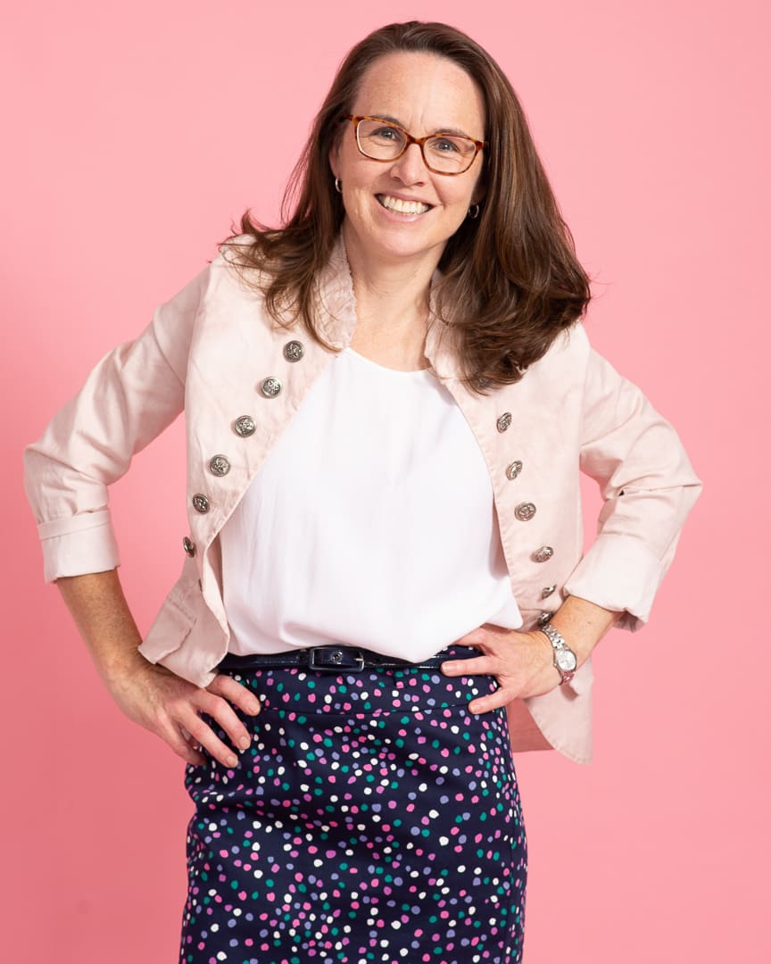 Woman poses with hands on hips and a smile for branding portrait.