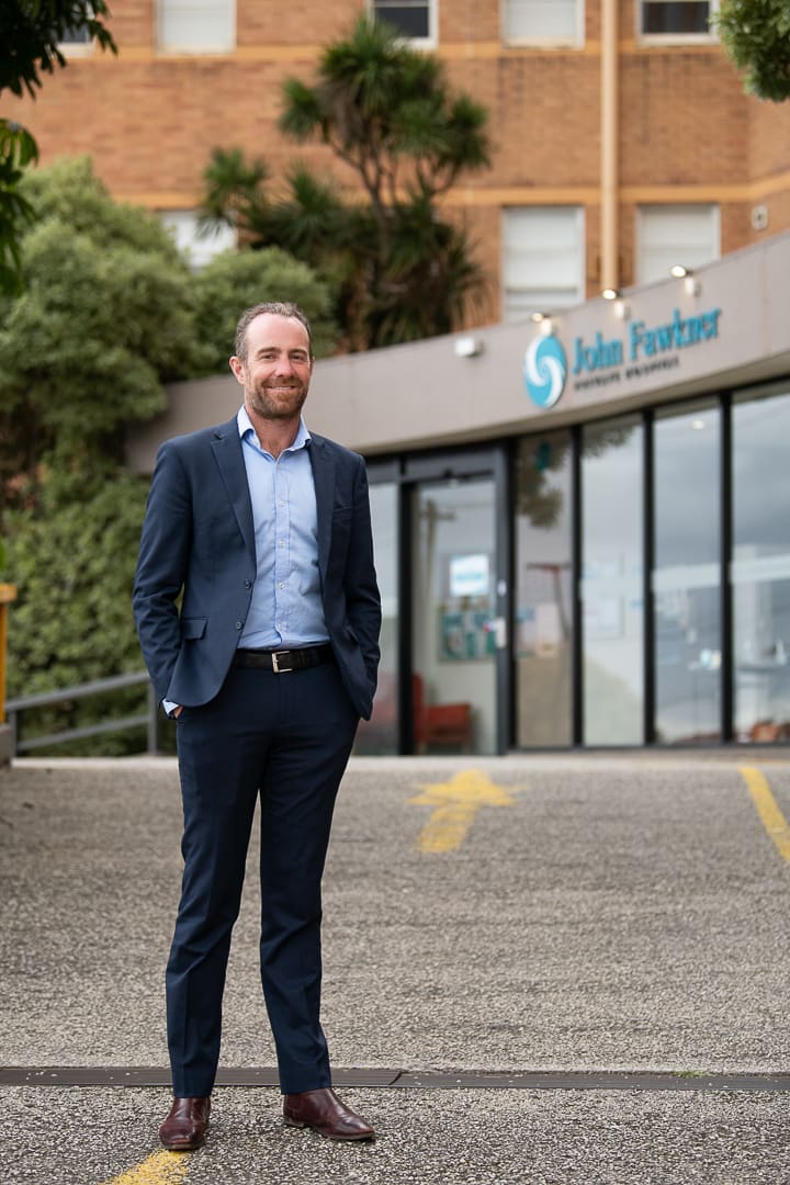 A melbourne doctor dressed in a suit stands outside a hospital for a professional doctors portrait