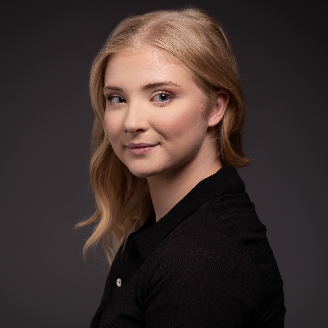 actor headshot taken in studio on a dark background. Melbourne woman smiles over her shoulder to camera.