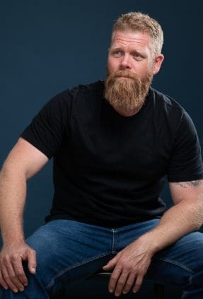 Melbourne actor sits and looks away with a serious expression in actor headshot.