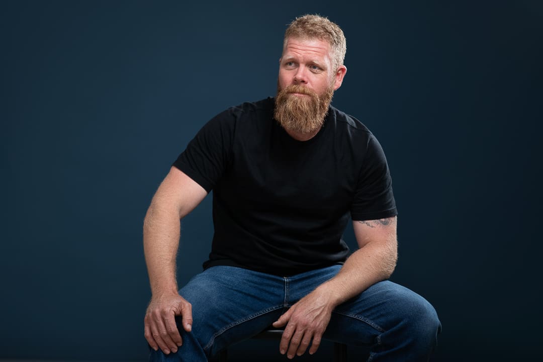 Melbourne actor sits and looks away with a serious expression in actor headshot.