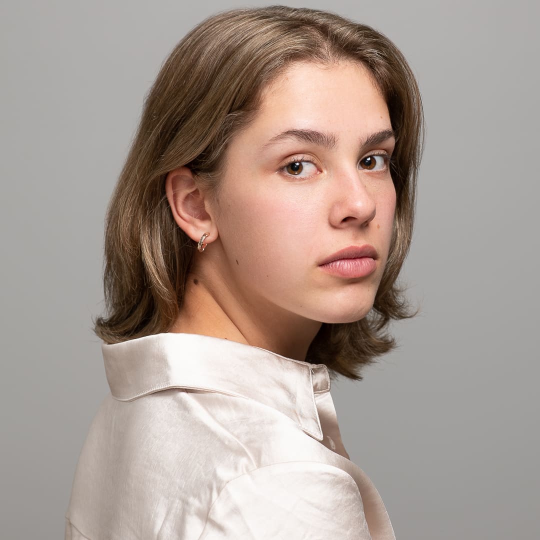 Melbourne actor poses for serious headshot taken in studio, looking over her shoulder directly to camera.