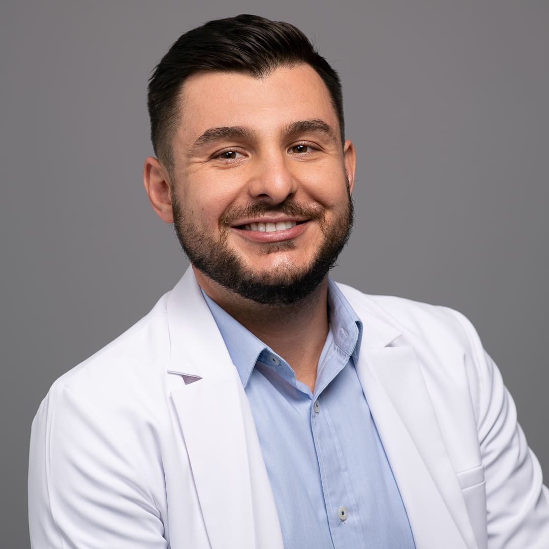 Professional doctor portrait of man wearing white doctors coat and smiling to camera.