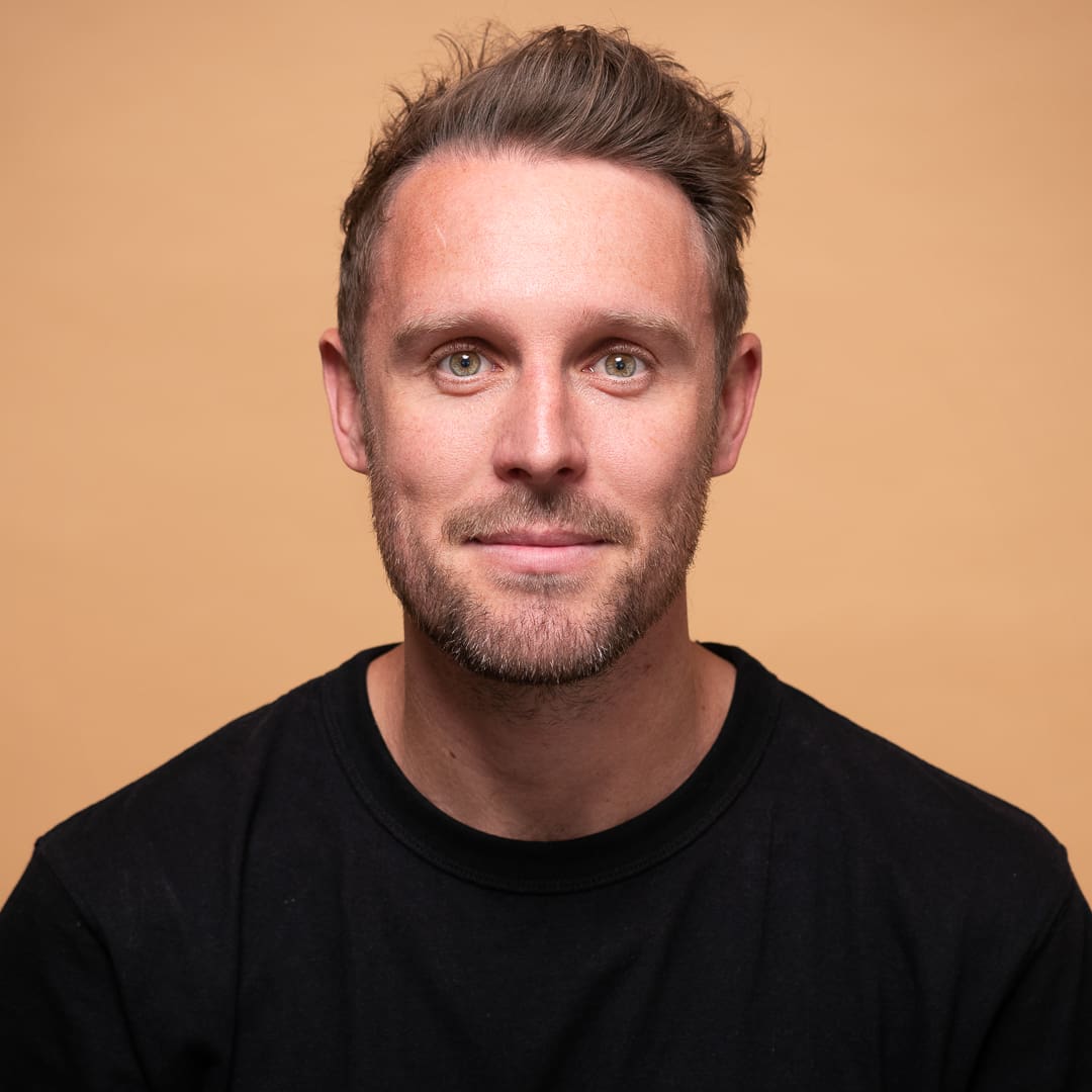 Modern corporate headshot of Melbourne man taken on an orange background