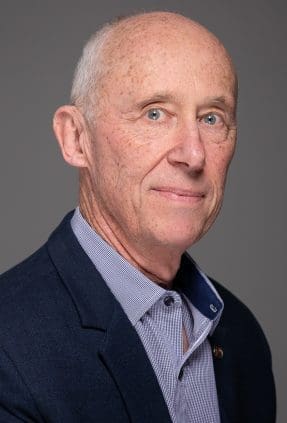 Professional headshot of Melbourne business owner on a grey background in studio.