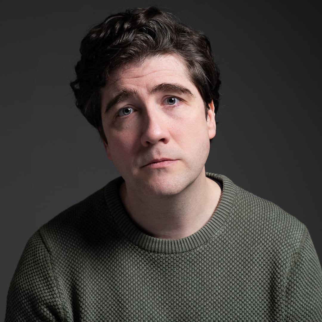 Melbourne actor pete wears an olive green jumper and is photographed for a headshot update in studio. His head is tilted back and he has a serious and vulnerable expression.