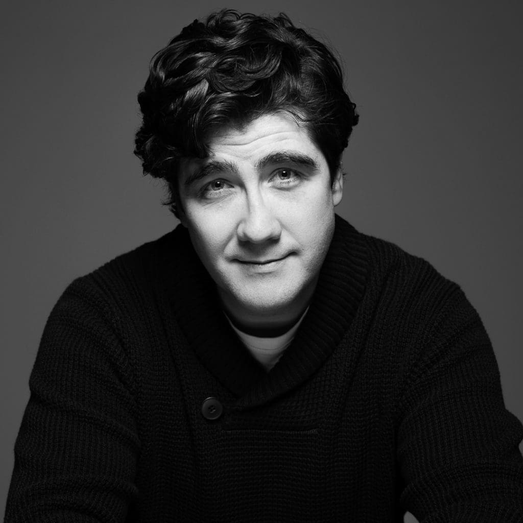 A black and white actor headshot of Melbourne actor Pete looking directly to camera with captivating eyes and a slight smile.