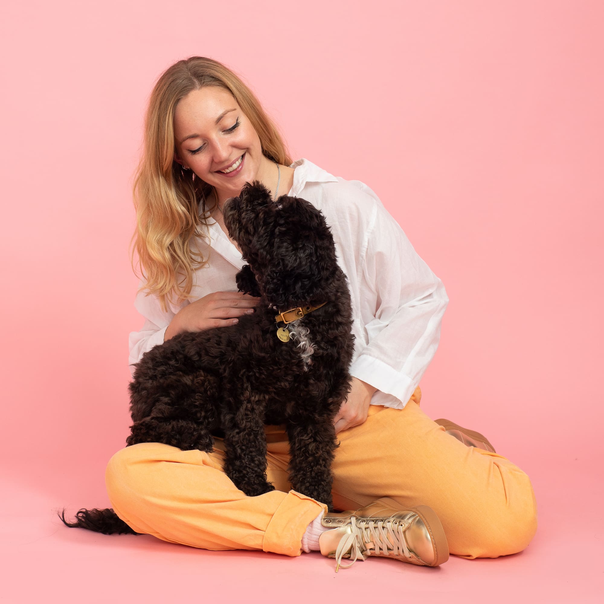 Personal branding portrait of smiling woman seated with black dog on her lap.