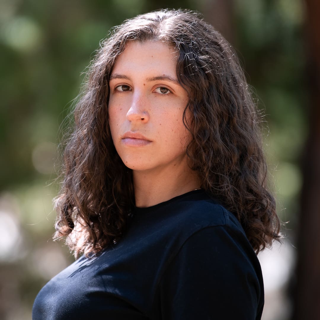 A melbourne actor headshot taken outdoors in natural light of woman looking directly to camera with a serious expression.