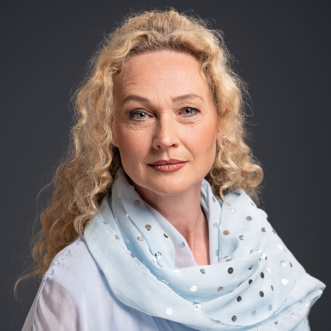 Glamour portrait of woman wearing a blue dotted scarf. She has a slight smile and captivating eyes.