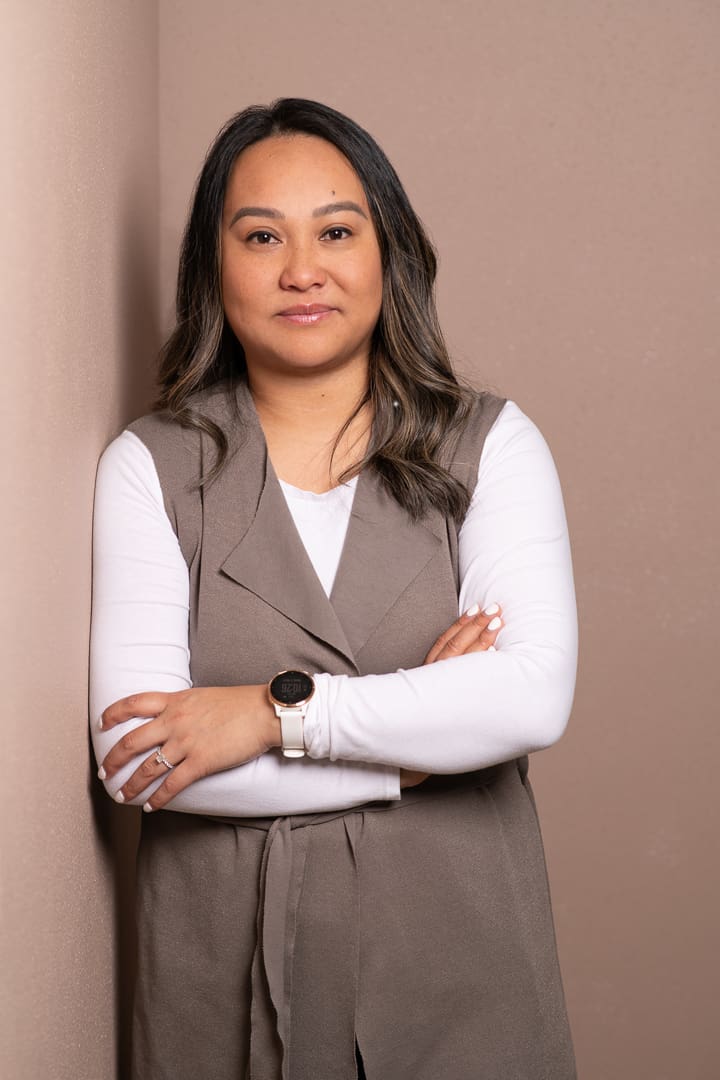 A personal branding portrait of melbourne mortgage broker, who stands leaning against a studio wall with a relaxed arms crossed pose, and is smiling to camera.