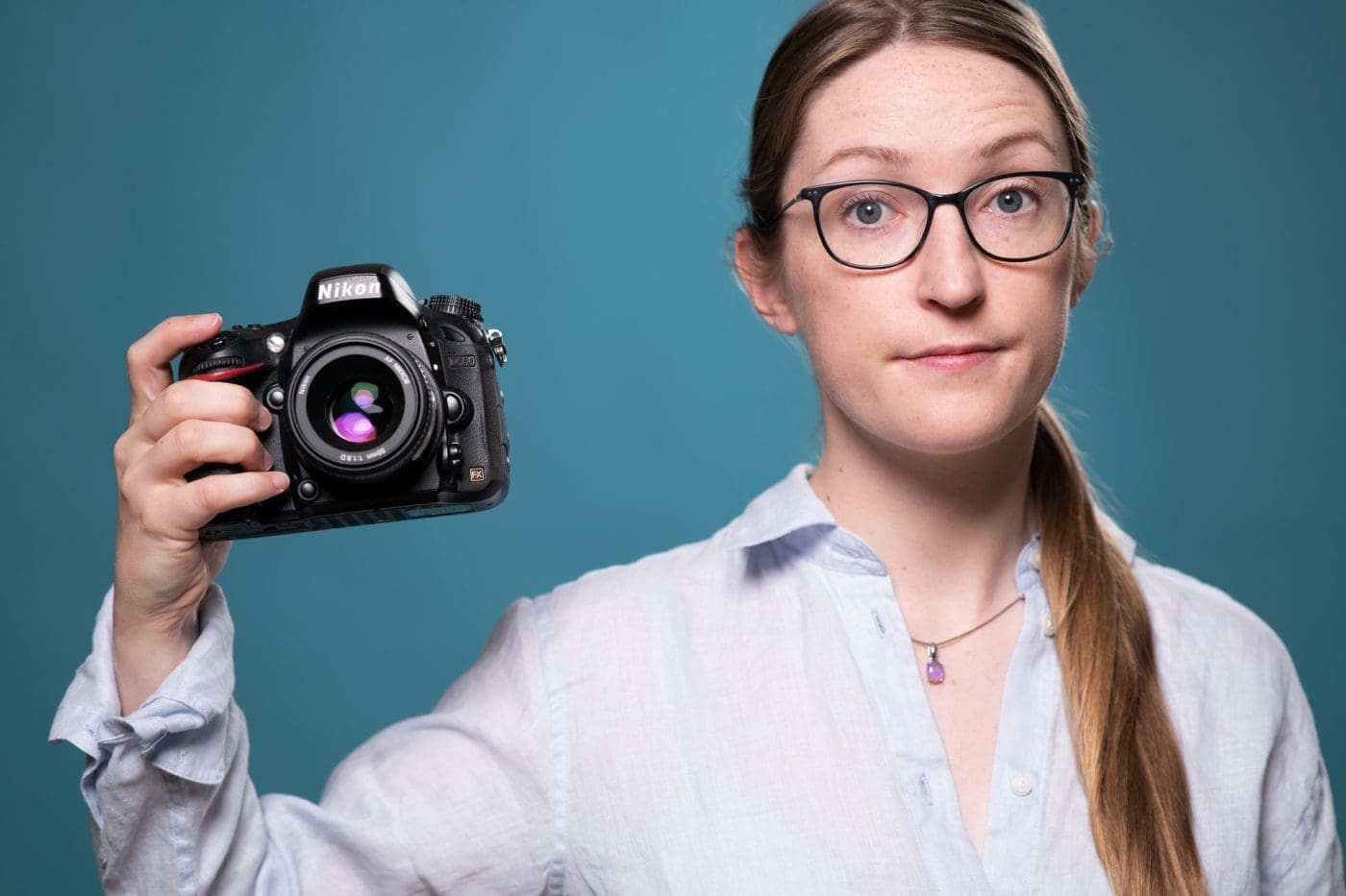 Portrait of Julia Nance holding a camera with a quirky expression.