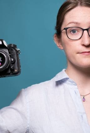 Portrait of Julia Nance holding a camera with a quirky expression.