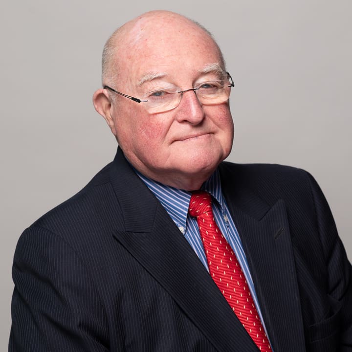 Melbourne LinkedIn headshot for local barrister, wearing a black suit, with blue shirt and red tie.