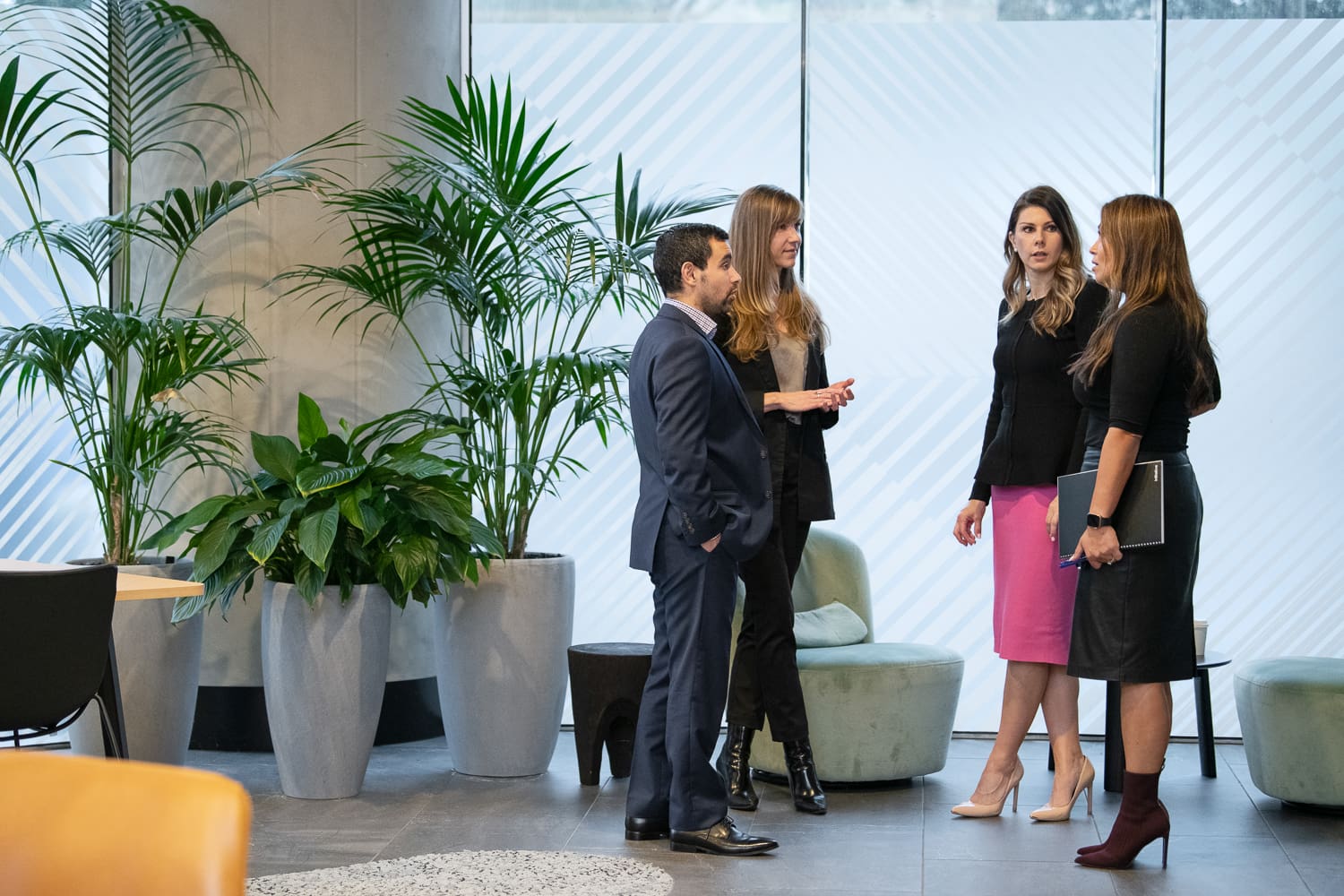 Personal branding photography of melbourne business - in-situ and working together in a collaborative way. A group of four team members stand and discuss in a modern interior setting.