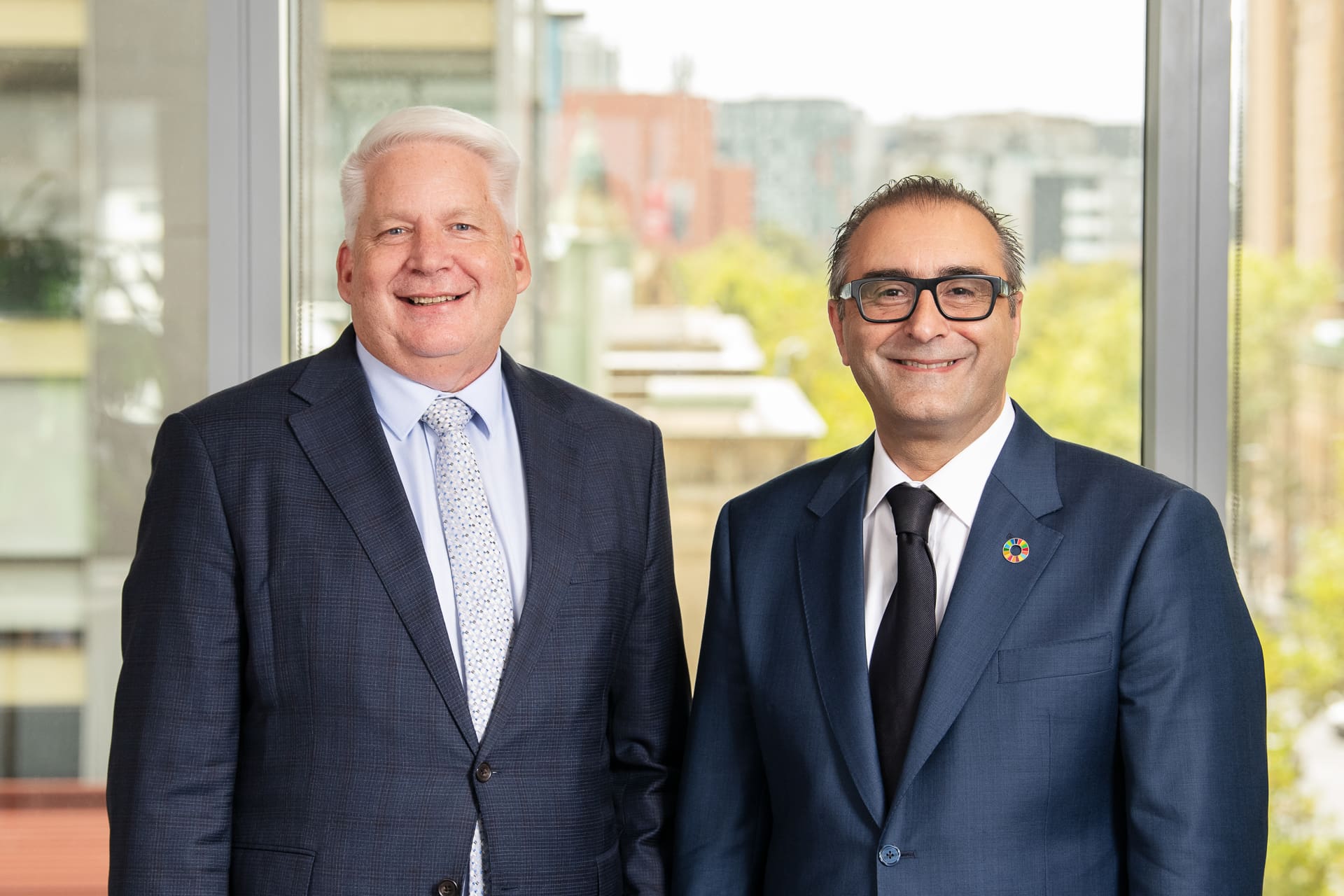 Corporate team partnership image of two CEO executives in front of Melbourne window scene.