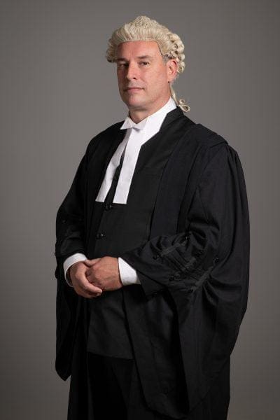 Corporate portrait of a barrister in traditional robes and wig.