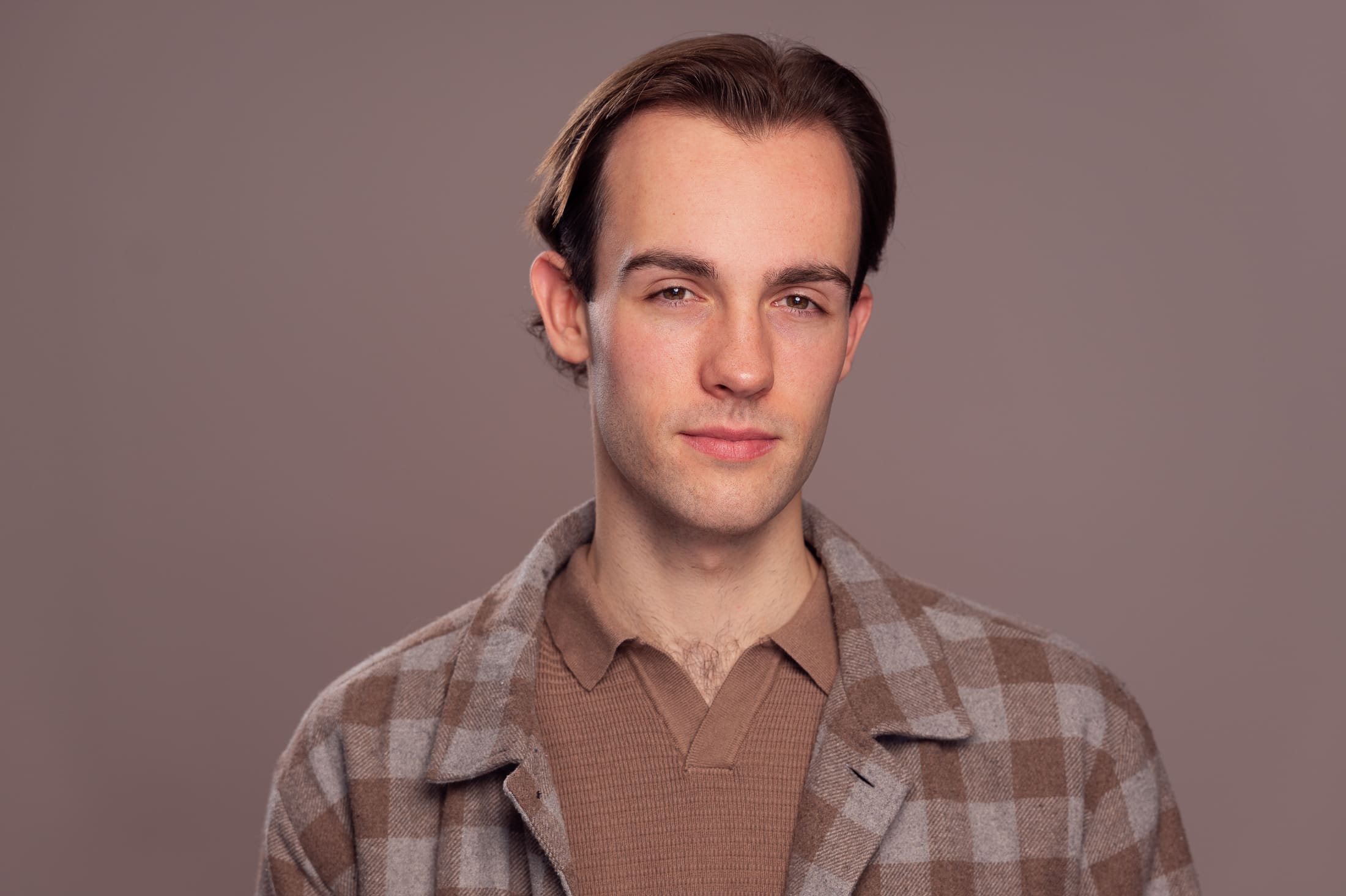 Man looks to camera with soft but serious expression.