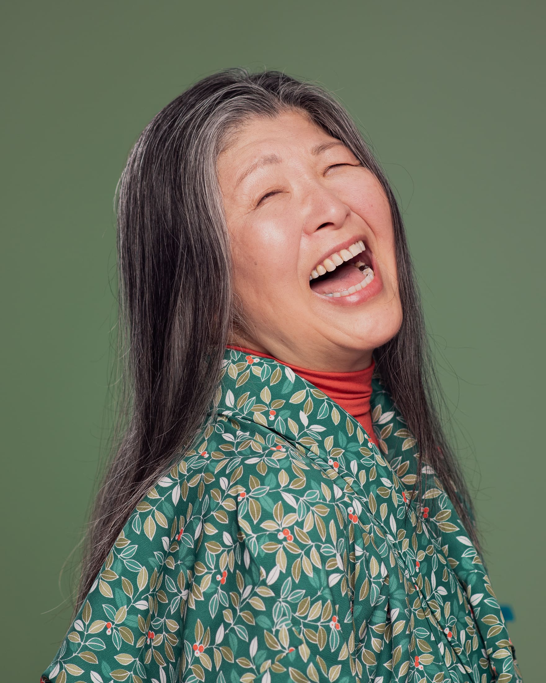 Woman laughing to camera. She wears a green patterned kimono.