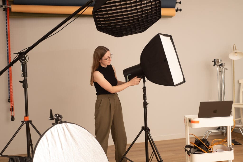 Julia is in her studio, adjusting lighting equipment.