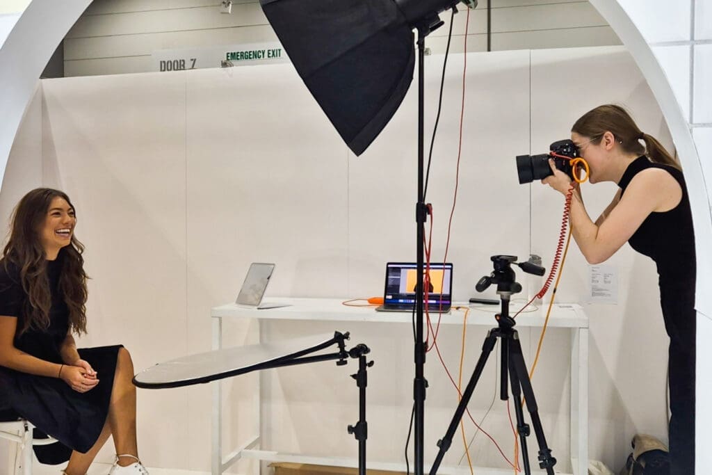 Julia takes a photograph of a smiling woman at a headshot event.